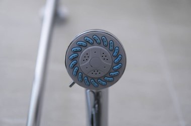 Modern banyoda modern duş başlığı. Banyoda su püskürtme veya su akışı olan duş başlığı. Rahatlamak ve özel banyoda eğlenmek. Bedenini temizlemek için duş başlığından taze su akıyor..