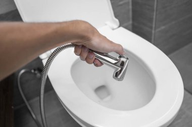 Beyaz tuvaletli bide duşu kullanmak. Beyaz klozet kullandıkları için erkek ellerinde bidet banyosu..