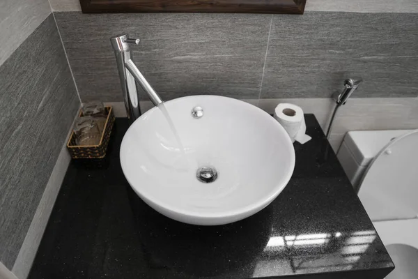 Modern bir banyoda beyaz yuvarlak lavabo ve krom musluk ile banyo içi. Krom musluktan akan su. — Stok fotoğraf