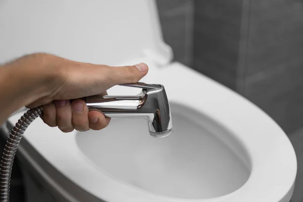 Použití bidetové sprchy s bílým WC. Bidet sprcha v mužské ruce pro použití s bílou toaletní mísou. — Stock fotografie