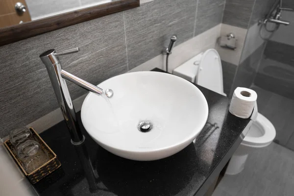 Εσωτερικό μπάνιο με λευκό στρογγυλό νεροχύτη και βρύση χρωμίου σε μοντέρνο μπάνιο. Νερό που ρέει από τη βρύση χρωμίου. — Φωτογραφία Αρχείου