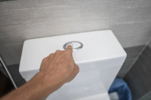 Primer plano del dedo presionando un botón de inodoro para limpiar un inodoro . — Foto de Stock