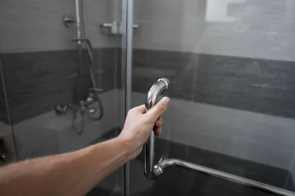 Mano masculina abre la puerta de la ducha en un baño moderno . —  Fotos de Stock