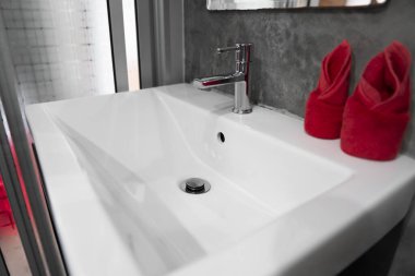 Üzerinde iki kırmızı havlu ile lavabo lavabo ile modern paslanmaz çelik musluk . Counter banyo iç çağdaş. Beton tarzı duvarlar ile lüks ve şık tasarım banyo.