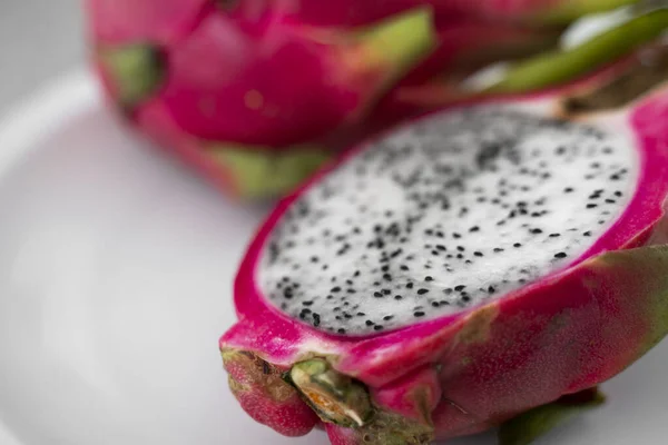 Frutto del drago. Vibrante Dragon Fruit su sfondo bianco. Fetta di frutta drago bianco o pitaya su piatto bianco sul tavolo, primo piano. Frutti tropicali ed esotici. Concetto di cibo sano e vitaminico . — Foto Stock