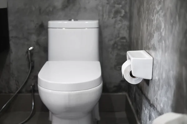 Siège de toilette suspendu blanc sur des toilettes blanches dans la salle de bain à la maison avec des carreaux gris en béton et du papier toilette sur le mur. Salle de bain luxe intérieur . — Photo
