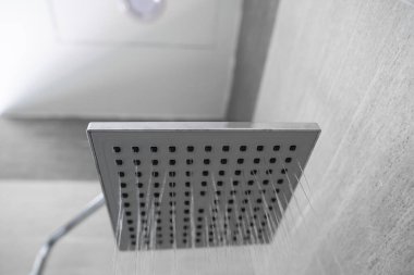 Modern bir banyodaki kare duş başlığından akan su. Banyoda su spreyi ya da suyla duş al. Duş başlığından temiz su akıntısı kirli bedeni temizlemek için..