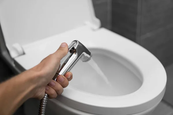 Korzystanie z bidetu prysznic z białą toaletą. Bidet prysznic w męskiej ręce do korzystania z białej muszli klozetowej. — Zdjęcie stockowe