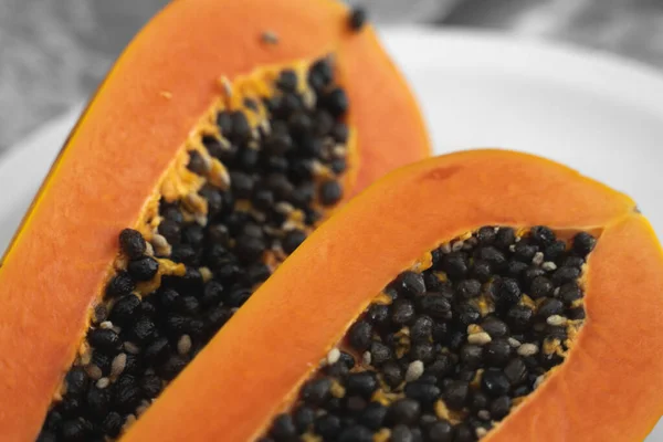 Half cut ripe papaya with seed on a white plate. Slices of sweet papaya with a white background. Halved papayas. Healthy exotic fruits. Vegetarian food. — ストック写真