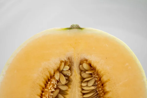 Frisse zoete sinaasappelmeloen op de witte plaat als achtergrond met een selectieve focus. Nuttig en vitaminerijk voedsel. Plantaardig. — Stockfoto