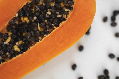 Beyaz bir tabakta tohum ile yarısı kesilmiş papaya. Beyaz arkaplanı olan tatlı papaya dilimleri. Yarım papayalar. Sağlıklı egzotik meyveler. Vejetaryen yemeği..