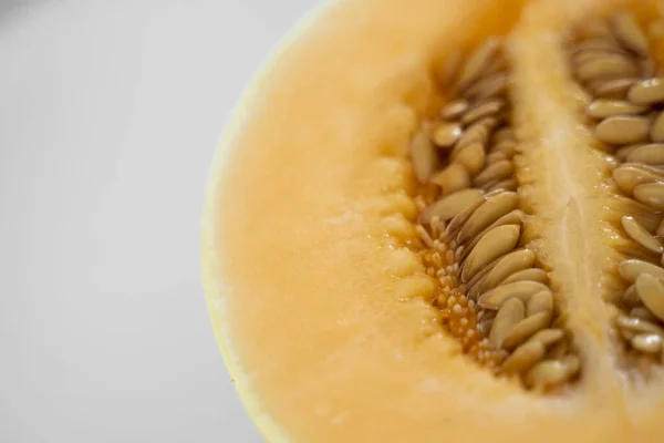 Frisse zoete sinaasappelmeloen op de witte plaat als achtergrond met een selectieve focus. Nuttig en vitaminerijk voedsel. Plantaardig. — Stockfoto