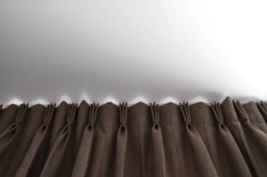 Beyaz tavanlı bir ray üzerinde kahverengi perdeler. Oturma veya uyku odasında perde iç dekorasyon. Kendi evinde rahat bir yaşam. Tatlı confy ev.