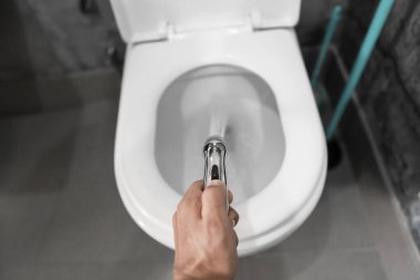 Beyaz tuvaletli bide duşu kullanmak. Beyaz klozet kullandıkları için erkek ellerinde bidet banyosu..