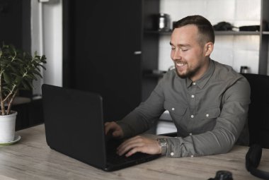 Happy Smile Genç işadamı veya öğrenci bilgisayar monitörü karşı oturan bir gömlek. Düşünceli bir ifade ile ofiste bir masada bir pc üzerinde çalışma.