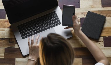 Kadın eli bilgisayarlı akıllı telefon kullanır. İnternette çalış ve çalış, serbest çalış. Serbest çalışan ya da serbest çalışan bir kadın, dizüstü bilgisayarıyla çalışan bir kız ahşap masada oturan bir telefon ve okuyucu..