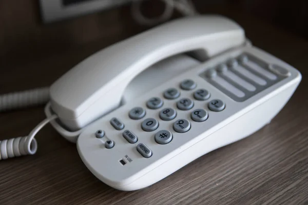 Vit Vintage telefon med gråa bataloder på ett brunt bord på hotellet. — Stockfoto