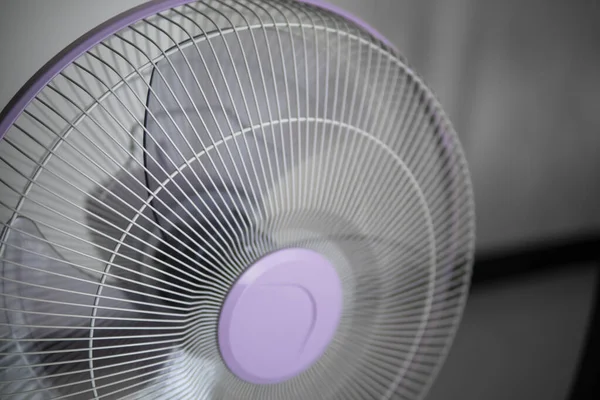 Modern violet electric fan in a living room saving peoples from hot temperature in summer days.