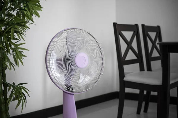 Moderno ventilador eléctrico violeta en una sala de estar salvando a la gente de la temperatura caliente en los días de verano . — Foto de Stock