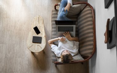 Kanepede dizüstü bilgisayarı olan bir kadın. İnternette çalış ve çalış, serbest çalış. Serbest çalışan bir kadın, defteriyle çalışan bir kız telefonla koltukta yatıyor, akıllı telefon ve kitap okuyor..