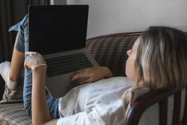 Kanepede dizüstü bilgisayarı olan bir kadın. İnternette çalış ve çalış, serbest çalış. Serbest çalışan bir kadın, defteriyle çalışan bir kız telefonla koltukta yatıyor, akıllı telefon ve kitap okuyor..