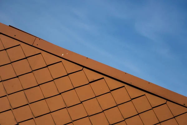 Telhas de telhado laranja natural em um edifício contra o céu azul . — Fotografia de Stock