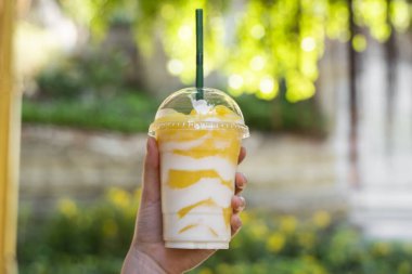 Yeşil arka planı olan bir pipetle plastik bardakta milkshake..