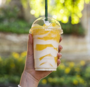 Yeşil arka planı olan bir pipetle plastik bardakta milkshake..