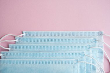 Pembe arka planda tıbbi koruyucu maskeler. Koronavirüsü önlemek için ağzı ve burnu kapamak için 3 katlı tıbbi maske. Coronavirus karantinası. Covid-19 'u korumak için antivirüs tıbbi maskesi.