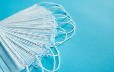 Mavi arka planda tıbbi koruyucu maskeler. Koronavirüsü önlemek için ağzı ve burnu kapamak için 3 katlı tıbbi maske. Coronavirus karantinası. Covid-19 'u korumak için antivirüs tıbbi maskesi.