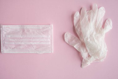 Tıbbi koruyucu maske ve lastik eldivenler pembe arka planda yatar. Covid-19 'a karşı anti-virüs koruma kiti. Coronavirus salgını 2019.
