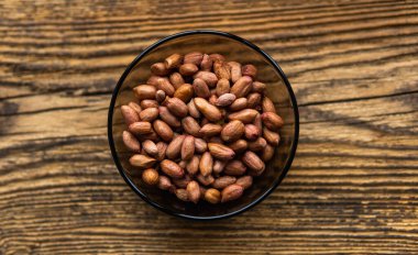 Eski ahşap bir masada, arka planda fotokopi alanı olan küçük bir tabakta yer fıstığı. Fıstık ezmesi sağlıklı bir vejetaryen proteindir..