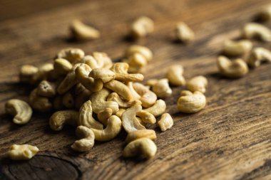 Ahşap şarap masasına saçılmış kaju fıstığı. Kaju fıstığı sağlıklı bir vejetaryen protein yiyeceğidir..