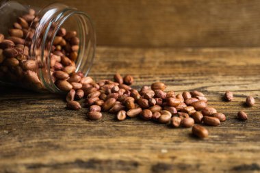 Fıstık ezmesi kavanozun içindeki ahşap şarap masasına saçılmış. Fıstık ezmesi sağlıklı bir vejetaryen proteindir..