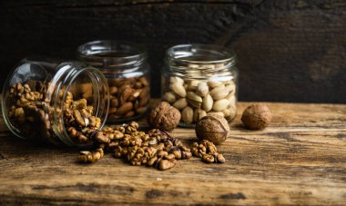 Ceviz, bir kavanozdan tüm cevizi kaplayan vintage masaya saçılmış. Ceviz sağlıklı bir vejetaryen protein besleyici gıdadır. Ceviz çekirdekleri ve eski ahşap cevizler..