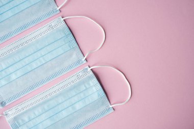 Pembe arka planda tıbbi koruyucu maskeler. Koronavirüsü önlemek için ağzı ve burnu kapamak için 3 katlı tıbbi maske. Coronavirus karantinası. Covid-19 'u korumak için antivirüs tıbbi maskesi.
