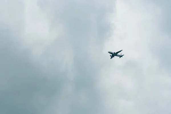Bulutlu bir gökyüzünde uçan uçak tropik bir adaya inmeye hazırlanıyor.. — Stok fotoğraf