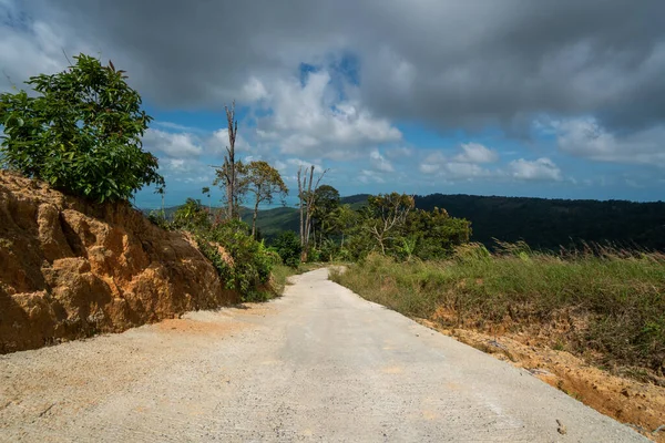 Un chemin de terre entre la jungle et les montagnes. Chemin de terre rural dans la forêt tropicale en Thaïlande . — Photo