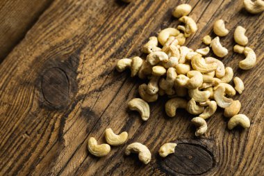 Ahşap şarap masasına saçılmış kaju fıstığı. Kaju fıstığı sağlıklı bir vejetaryen protein yiyeceğidir..