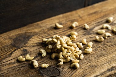 Ahşap şarap masasına saçılmış kaju fıstığı. Kaju fıstığı sağlıklı bir vejetaryen protein yiyeceğidir..