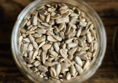 Ayçiçeği tohumları küçük bir kavanozda, ahşap şarap masasının üzerinde. Sağlıklı vejetaryen protein besleyici gıdalar. Kırsal kesimde ayçiçeği tohumu.
