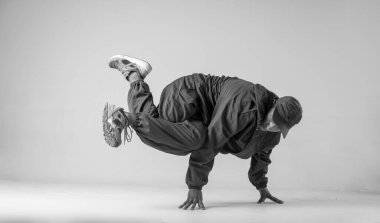 Bir hip hop dansçısı ya da bboy beyaz arka planda bir pozda donar. Bboy şık numaralar yapıyor..