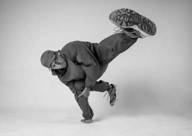 Bir hip hop dansçısı ya da bboy beyaz arka planda bir pozda donar. Bboy şık numaralar yapıyor..