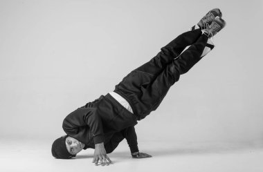 Bir hip hop dansçısı ya da bboy beyaz arka planda bir pozda donar. Bboy şık numaralar yapıyor..