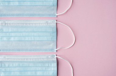 Pembe arka planda tıbbi koruyucu maskeler. Koronavirüsü önlemek için ağzı ve burnu kapamak için 3 katlı tıbbi maske. Coronavirus karantinası. Covid-19 'u korumak için antivirüs tıbbi maskesi.