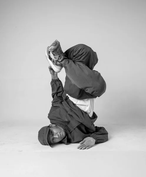 Un uomo ballerino hip hop o bboy si blocca in una posa su uno sfondo bianco. ragazzo facendo elegante acrobazie . — Foto Stock