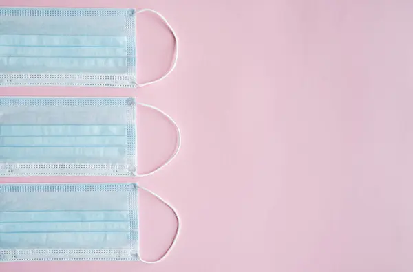 Máscaras de proteção médica em um fundo rosa. Máscara médica descartável de 3 camadas para cobrir a boca e o nariz para prevenir o coronavírus. Quarentena do Coronavírus. Máscara médica antivírus para proteção covid-19 . — Fotografia de Stock