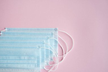 Pembe arka planda tıbbi koruyucu maskeler. Koronavirüsü önlemek için ağzı ve burnu kapamak için 3 katlı tıbbi maske. Coronavirus karantinası. Covid-19 'u korumak için antivirüs tıbbi maskesi.