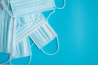 Mavi arka planda tıbbi koruyucu maskeler. Koronavirüsü önlemek için ağzı ve burnu kapamak için 3 katlı tıbbi maske. Coronavirus karantinası. Covid-19 'u korumak için antivirüs tıbbi maskesi.