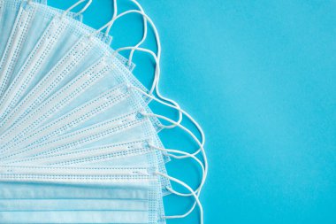 Mavi arka planda tıbbi koruyucu maskeler. Koronavirüsü önlemek için ağzı ve burnu kapamak için 3 katlı tıbbi maske. Coronavirus karantinası. Covid-19 'u korumak için antivirüs tıbbi maskesi.